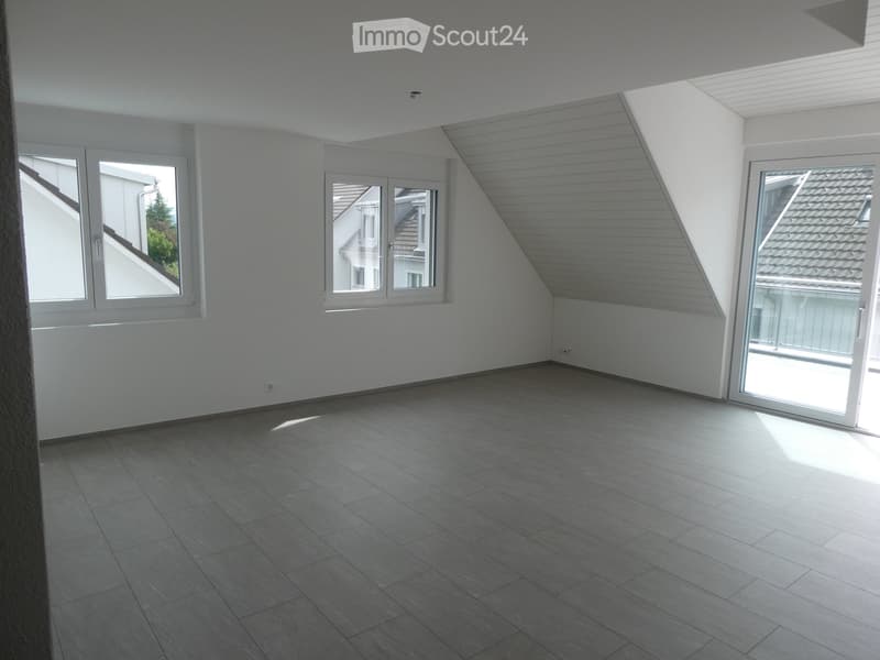Empty room with white walls, grey tiled floor, large windows, and a sliding glass door leading to a balcony.