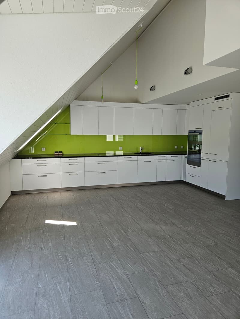 Modern kitchen with white cabinets, grey tiled floor, green backsplash, and built-in oven.