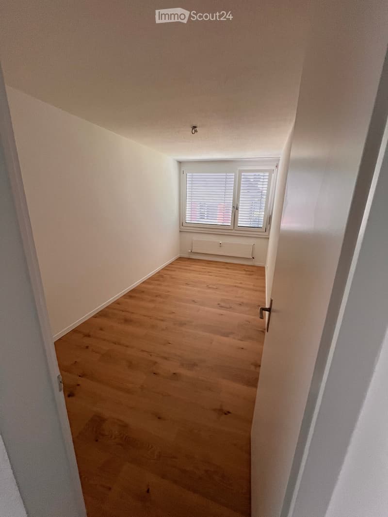 Empty room with wooden flooring, white walls, and a window with blinds. No furniture or equipment present.