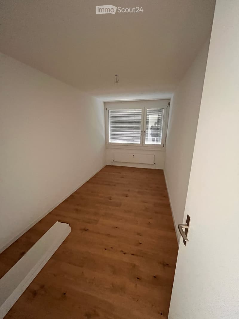 Empty room with light-colored walls, wooden floor, and a window with blinds. No furniture or equipment is present.