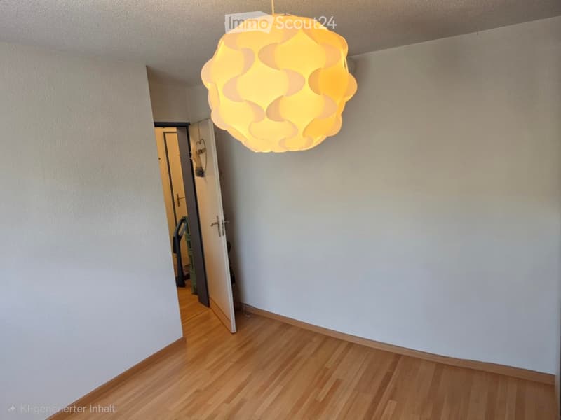 Empty hallway with light wooden flooring, white walls, and a modern hanging light fixture. An open doorway leads to another room.