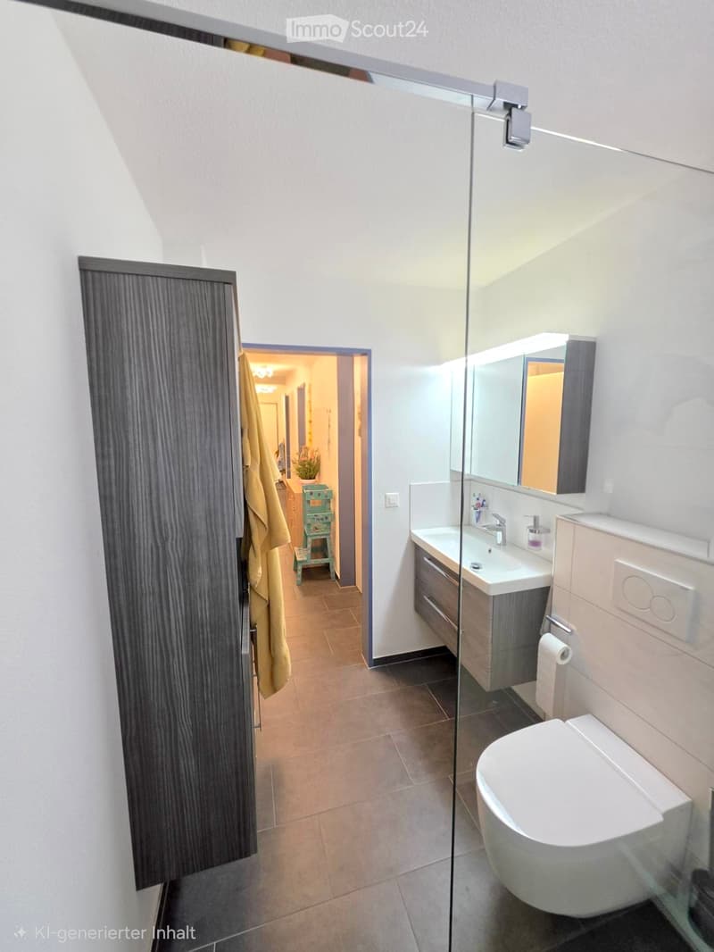 Modern bathroom with a white sink, mirror, and toilet. Features a glass shower enclosure and a wooden cabinet.