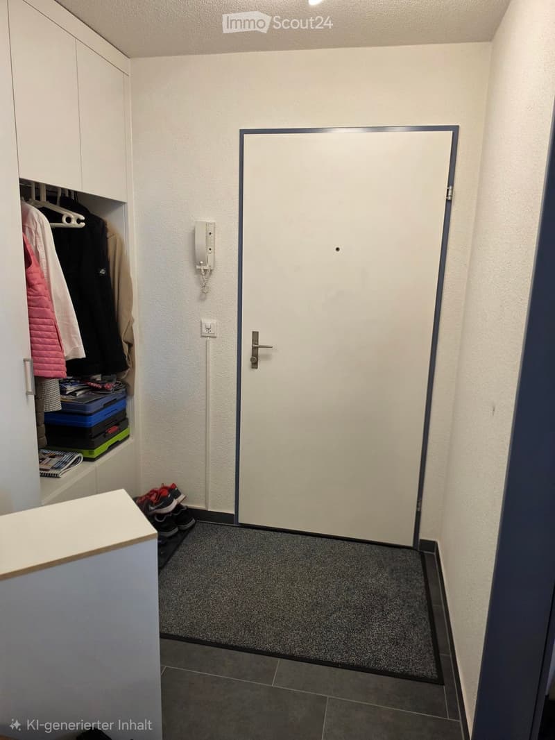 A narrow hallway with a closed door, a small cabinet with clothes and storage boxes, a telephone, and a pair of shoes on the floor.