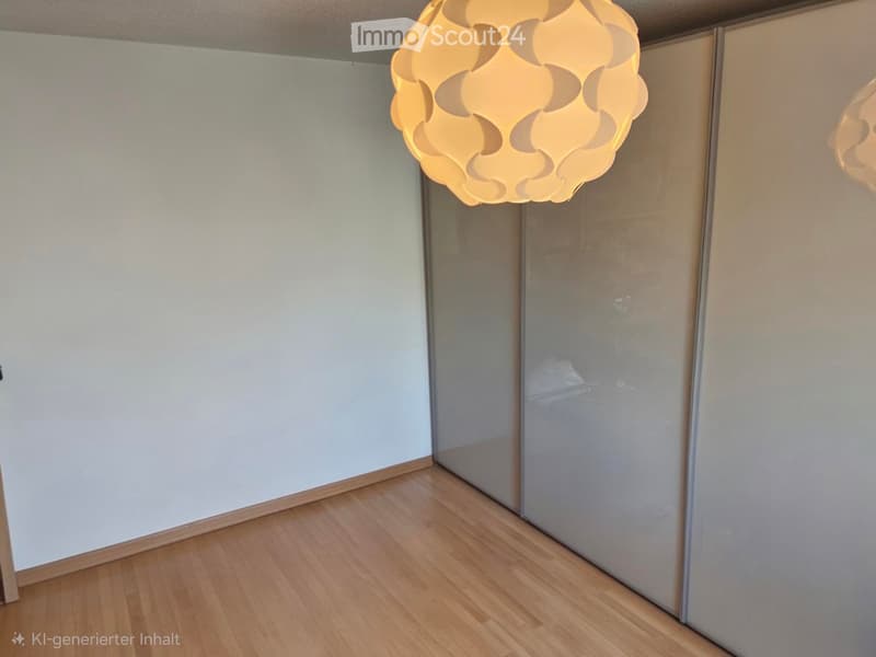 Empty room with light-colored walls, wooden flooring, and a modern pendant light fixture hanging from the ceiling. The room features a set of sliding glass doors leading to another space.