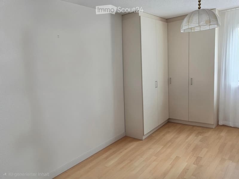Empty room with light wooden flooring, white walls, built-in wardrobes, and a hanging light fixture.