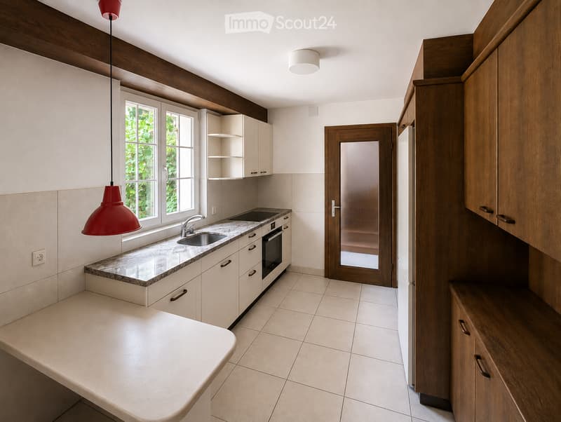 Modern kitchen with white cabinets, marble countertop, stainless steel sink, and built-in oven. Features a pendant light and a window with a view of greenery.