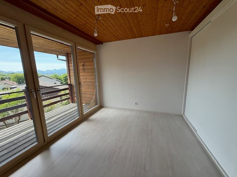 Empty room with wooden flooring, white walls, and large sliding glass doors leading to a balcony.
