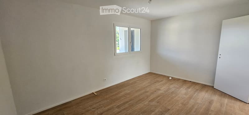 Empty room with wooden flooring, white walls, and a single window with white frame. No furniture or equipment present.