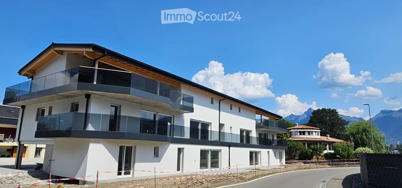 Modern two-story house with white facade, large windows, and multiple balconies overlooking a scenic mountain view.