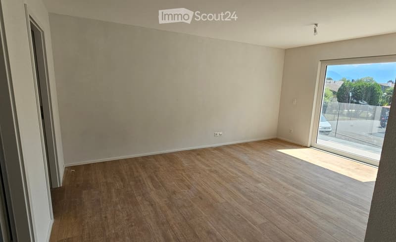 Empty room with wooden flooring, white walls, and a large sliding glass door leading to an outdoor area.