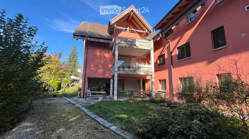 Two story house, red brick, brown roof, balcony, garden, outdoor seating area