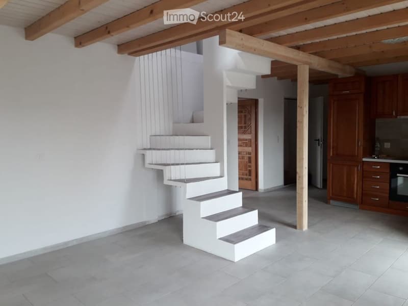 Modern, minimalist interior with white staircase, wooden beams, and grey tiled floor. No furniture or equipment visible.