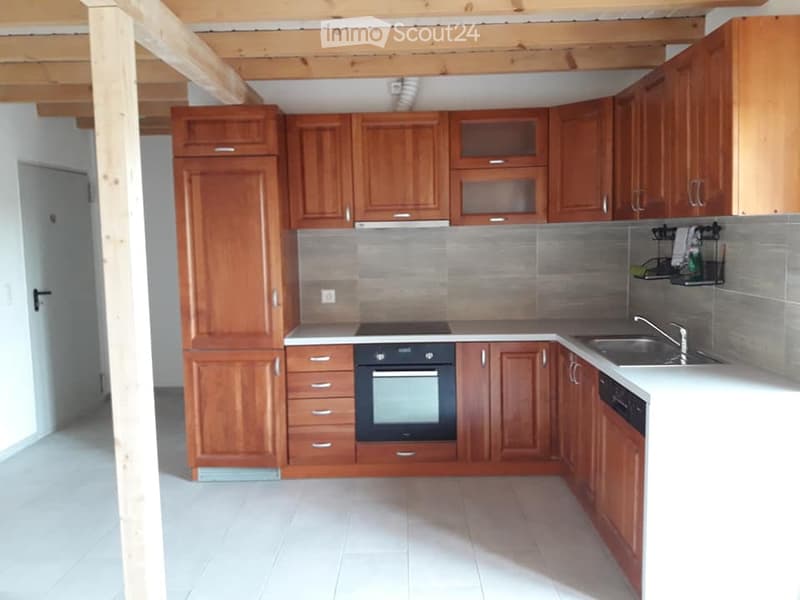 Modern kitchen with wooden cabinets, stainless steel appliances, and white countertops.