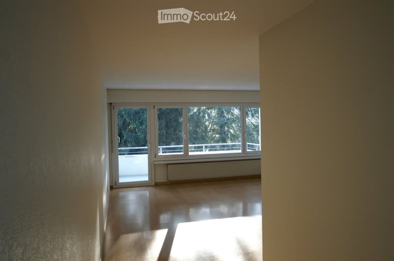 Empty room with wooden flooring, large windows, and a radiator. No furniture or equipment present.