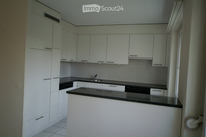 Modern kitchen with white cabinets, black countertops, and stainless steel sink and faucet.