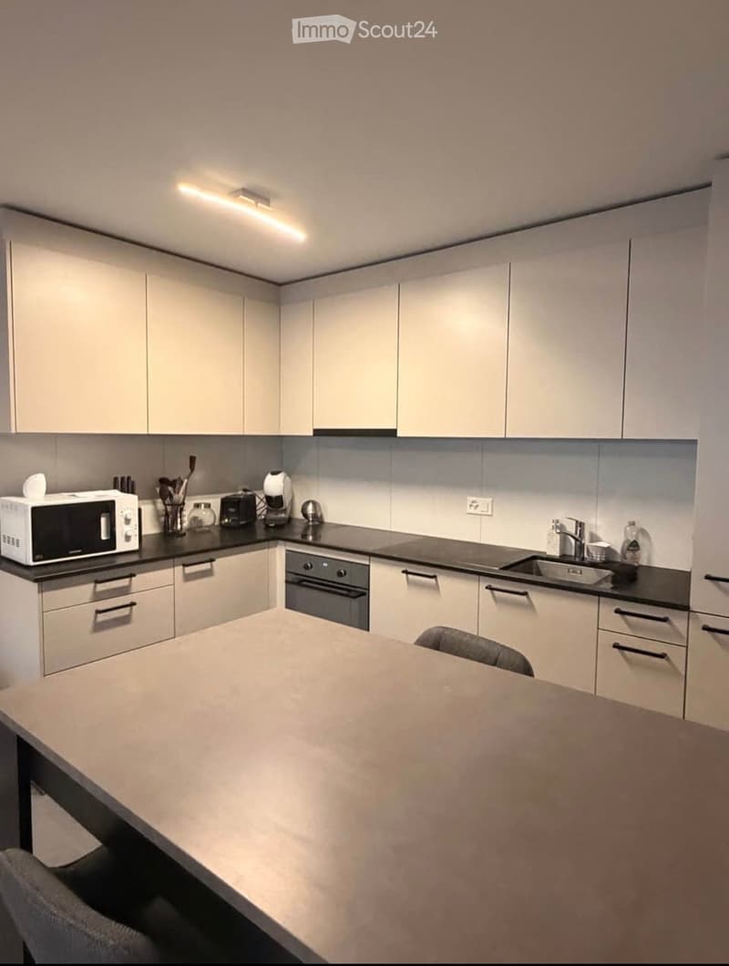 Modern kitchen with white cabinets, stainless steel appliances, and a large island with a dark countertop.