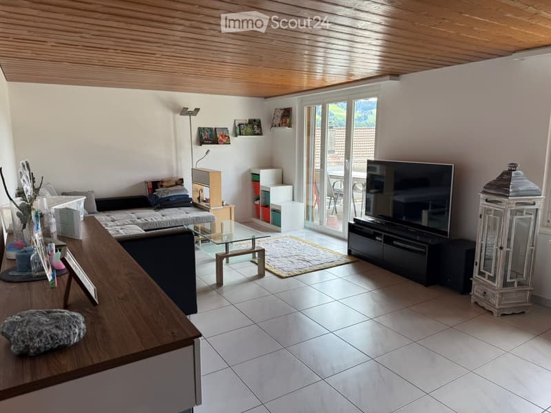 Modern living room with a wooden ceiling, white tiled floor, large sliding glass doors leading to a patio, a sectional sofa, a glass coffee table, a TV stand, shelves, and a decorative lantern.
