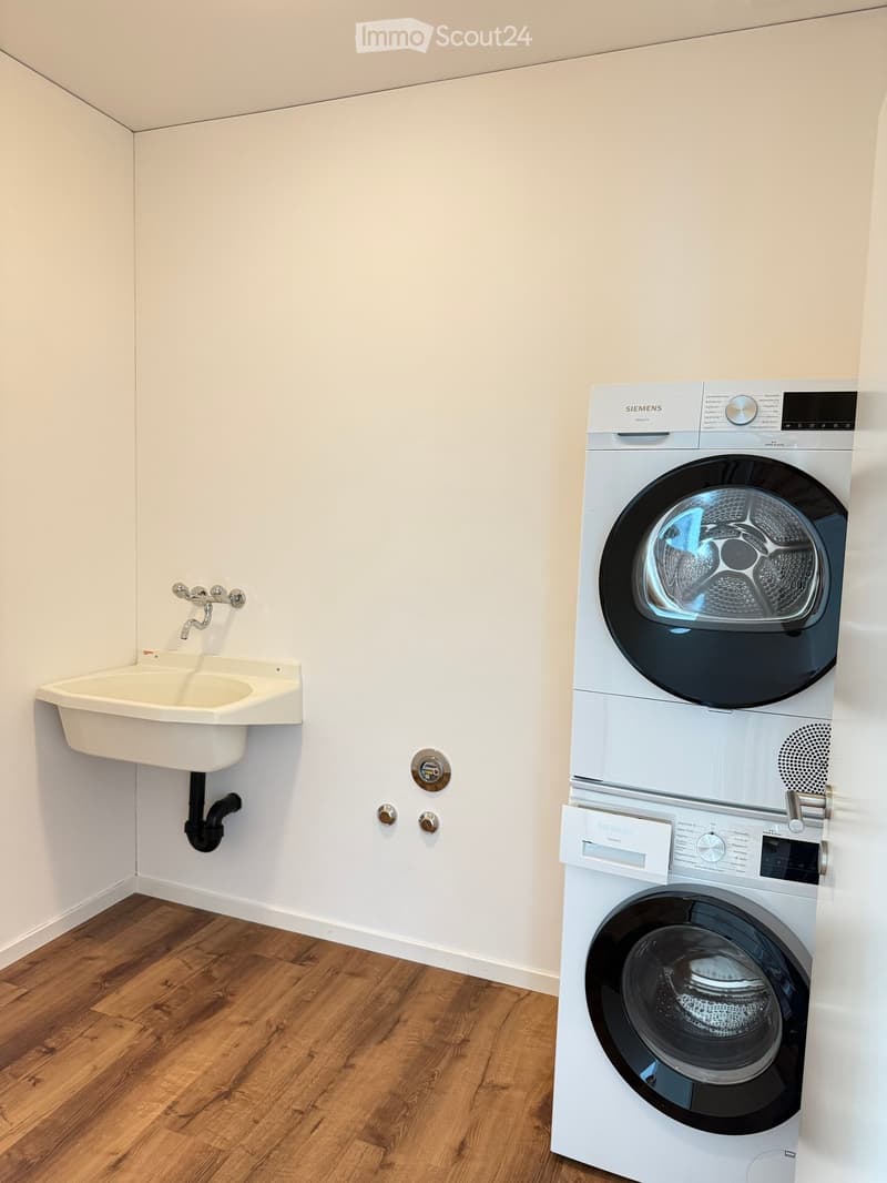 Bathroom with a white sink, a washing machine, and a dryer unit.