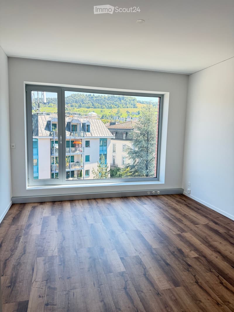 Empty room with wooden flooring and large window offering a scenic view of the surrounding landscape.