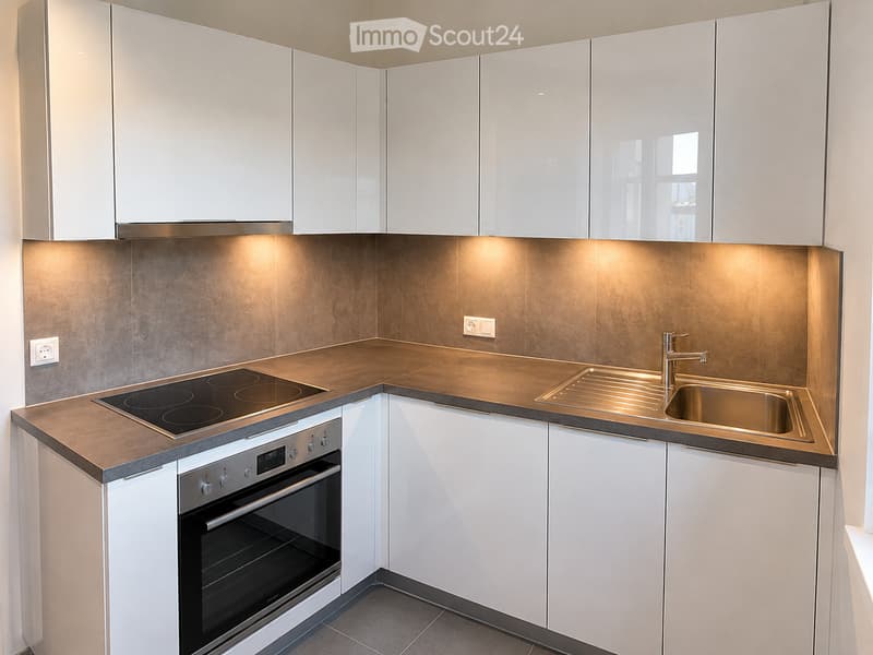 Modern kitchen with white cabinets, stainless steel appliances, and a brown countertop.
