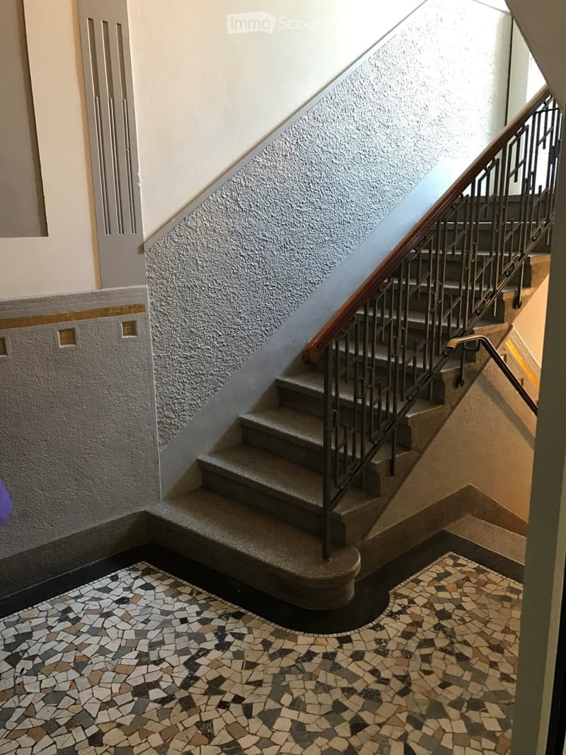 Staircase with metal railing and patterned mosaic tile floor, leading to an upper level.
