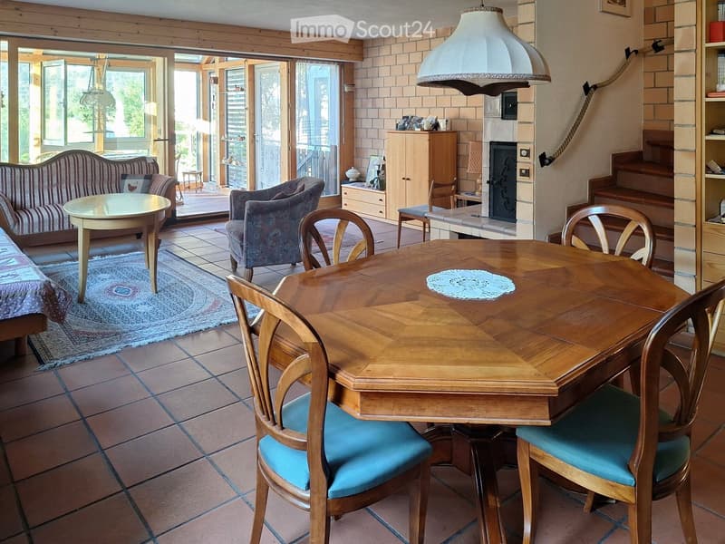 Cozy living and dining area with a sofa, dining table, chairs, fireplace, and cabinet.