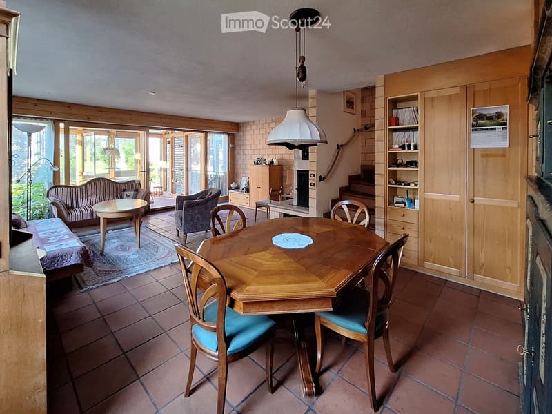 Bright living and dining area with a fireplace, large windows, and a mix of seating and dining furniture.