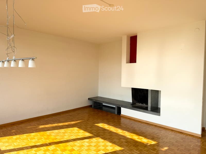 Empty room with light-colored walls, wooden floor, and a built-in fireplace with a bench. No furniture or equipment present.