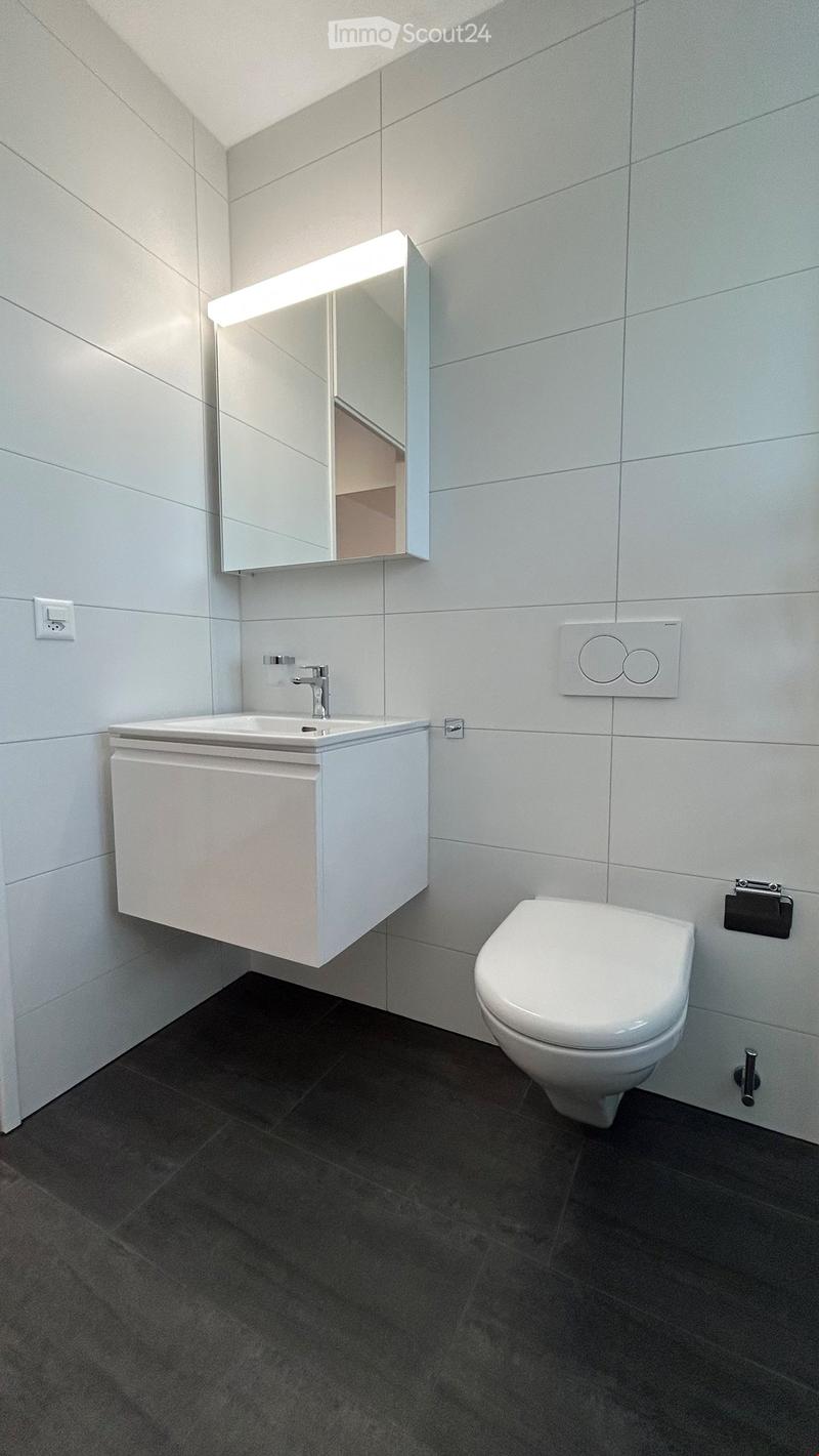 modern bathroom with white tiles, white sink, white toilet, mirror, power outlet