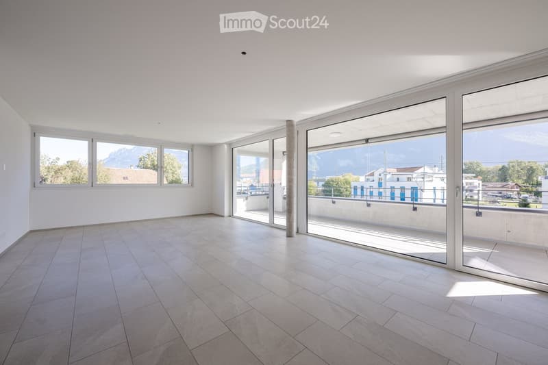 Empty room with large windows and sliding glass doors leading to a balcony, featuring tiled flooring and white walls.