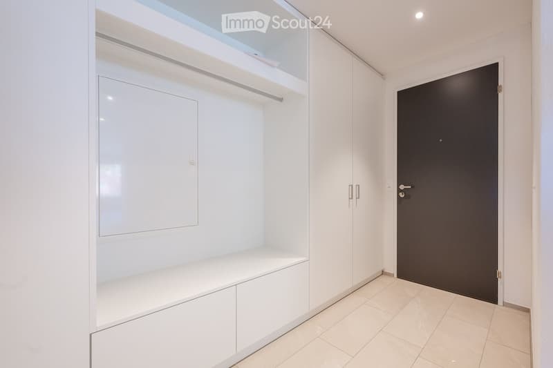Entrance hall with white cabinets, tiled floor, and a door.