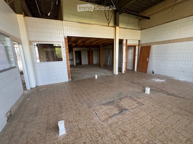 Empty room with tiled walls, wooden floor, and several doors leading to other spaces. No furniture or equipment present.