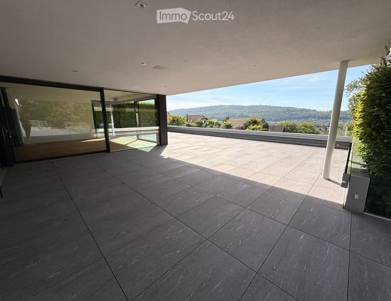 Modern balcony with large glass sliding doors, tiled floor, and scenic mountain view.
