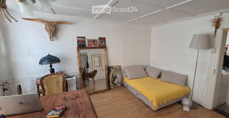 Cozy living room with a yellow sofa, wooden table, laptop, decorative mirror, and a floor lamp.