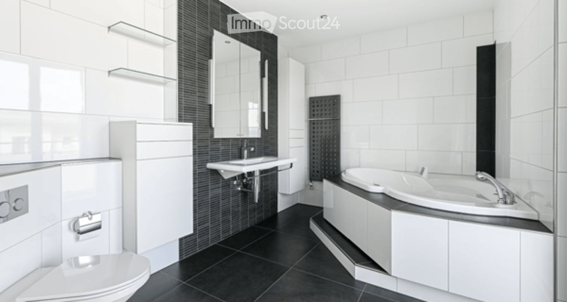 Modern bathroom with white tiles, black accents, a bathtub, toilet, sink, and glass shelves.