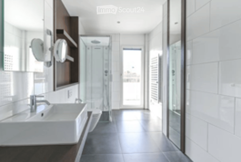 Modern bathroom with white tiles, a large sink, a mirror, and a glass-enclosed shower area.