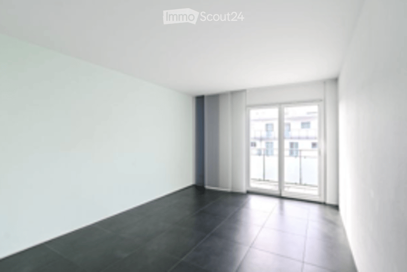 Empty room with dark tiled floor, white walls, large window with blinds, and a glass door leading to a balcony.