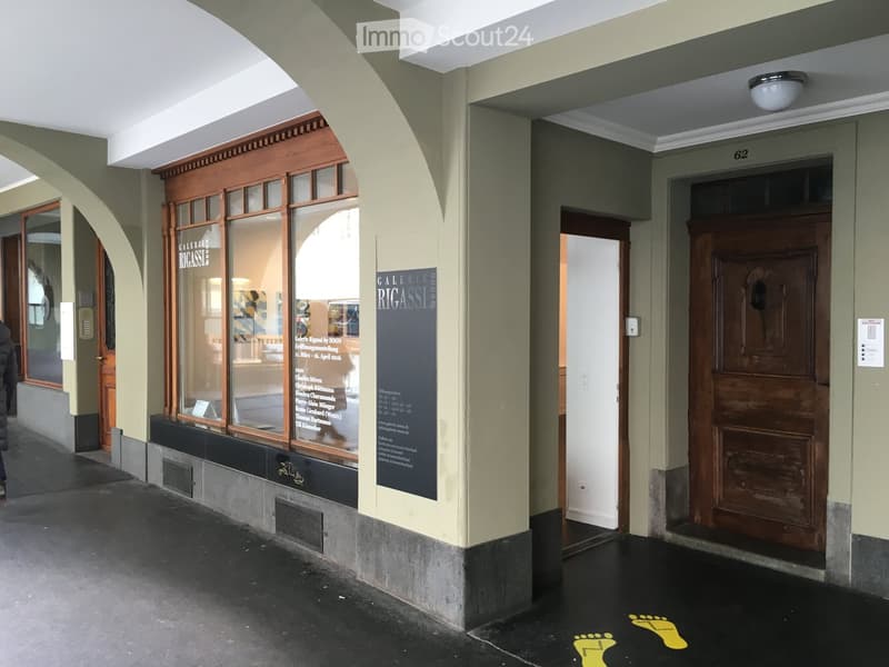 A hallway with arched doorways, a gallery sign, and a wooden door labeled '62'.