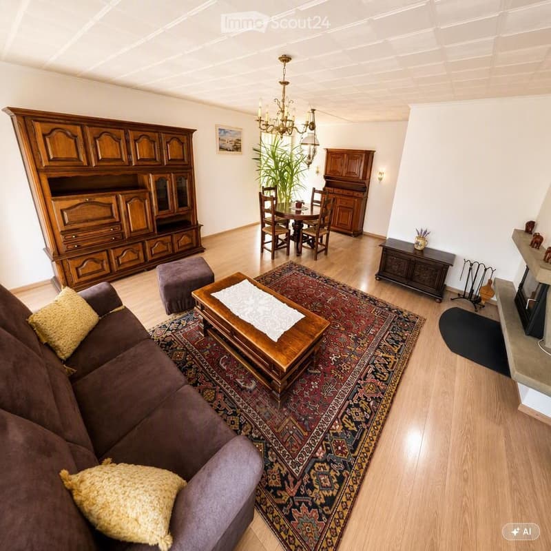 A well-furnished living room with a brown sofa, wooden coffee table, ottoman, dining area with a table and chairs, wooden cabinets, chandelier, and a fireplace.