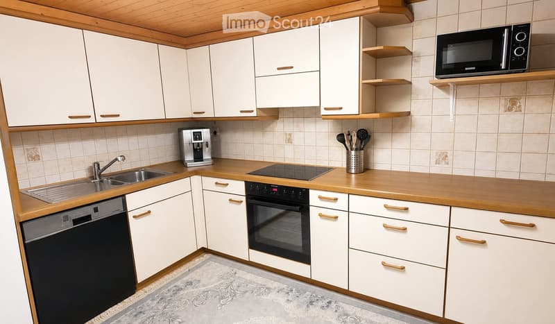 Modern kitchen with white cabinets, wooden countertops, stainless steel sink, coffee maker, oven, microwave, and various kitchen utensils.