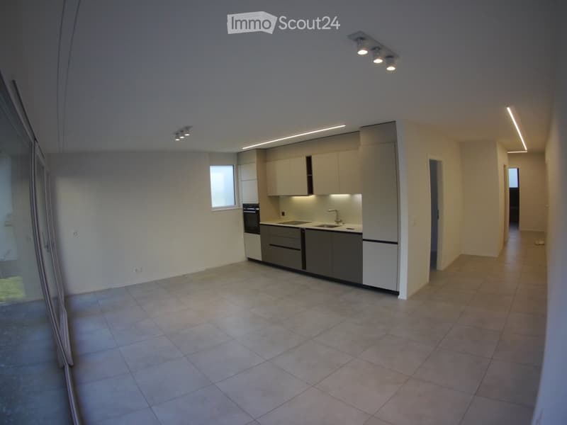 Empty kitchen area with tiled floor, white cabinets, sink, and stove. No furniture or appliances are present.