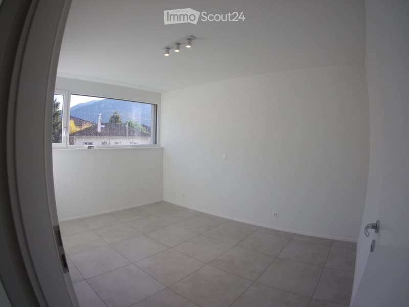 Empty room with tiled floor, white walls, large window with a scenic mountain view, and recessed ceiling lights.