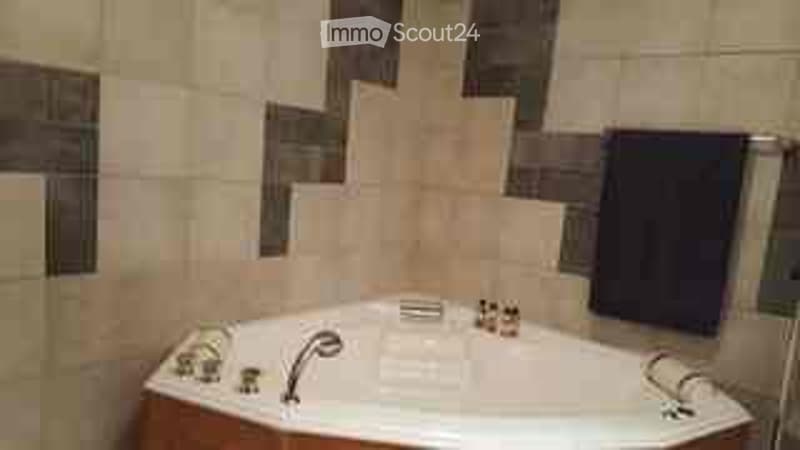 Bathroom with a modern bathtub, tiled walls, and a dark towel hanging on the wall.