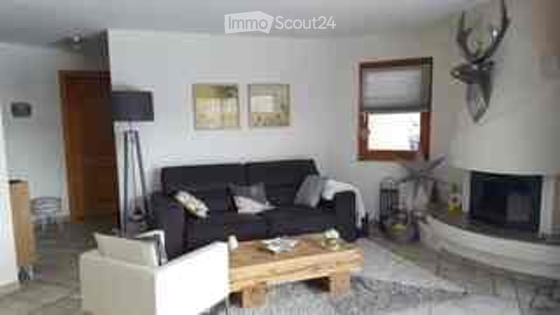 Living room with a black sofa, white armchair, coffee table, floor lamp, fireplace, and picture frames on the wall.