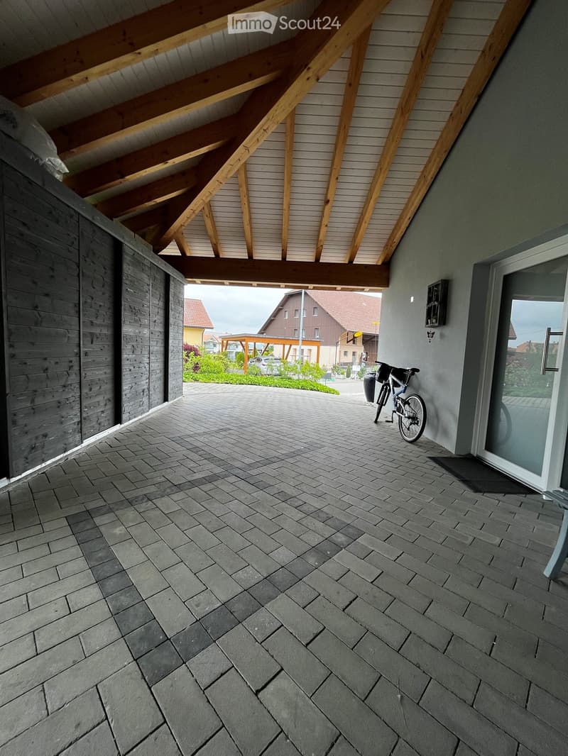 Balcony with stone tiled floor, wooden ceiling beams, and a bicycle leaning against the wall.