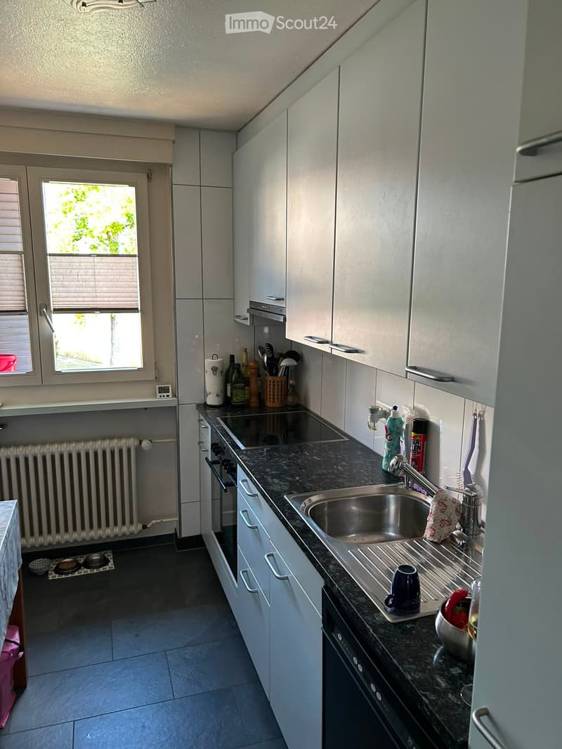 Modern kitchen with white cabinets, granite countertop, stainless steel sink, and various appliances.