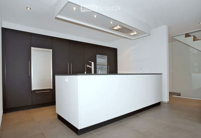 Modern kitchen with a white island, dark cabinets, and stainless steel appliances.