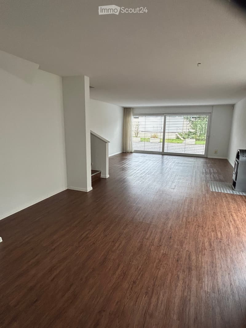 Empty room with wooden flooring, white walls, and a large sliding glass door leading to an outdoor area.