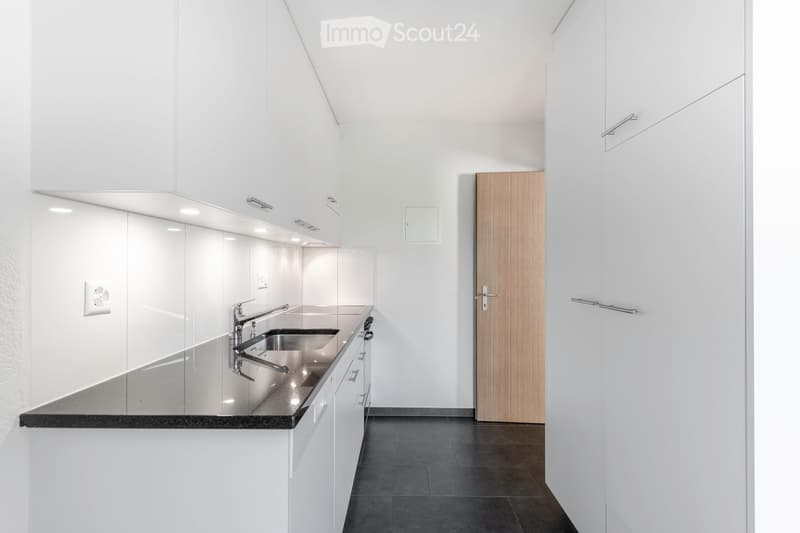 Modern kitchen with white cabinets, stainless steel sink, and sleek countertops.