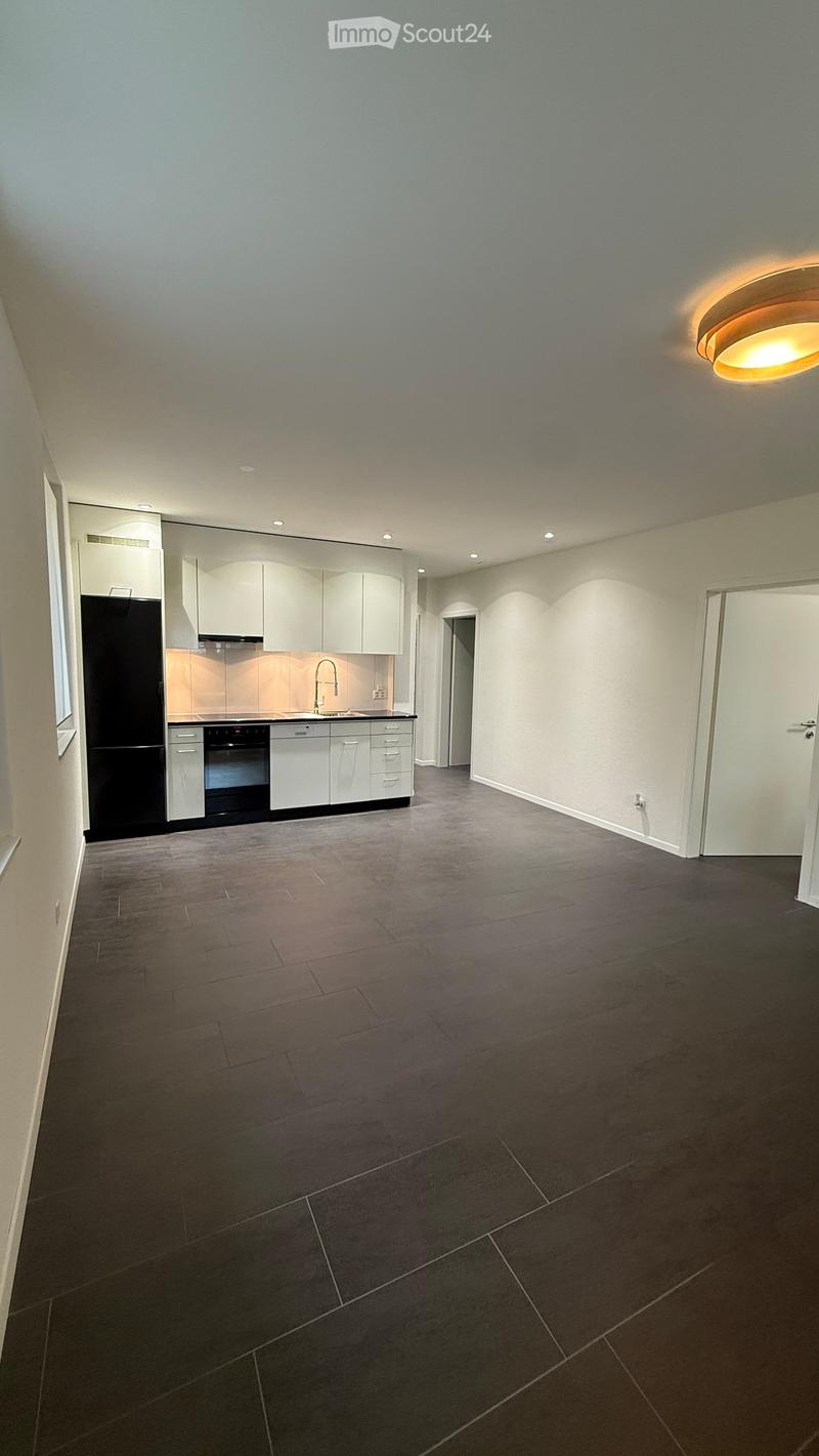 Empty kitchen with white cabinets, black appliances, and dark tiled flooring.